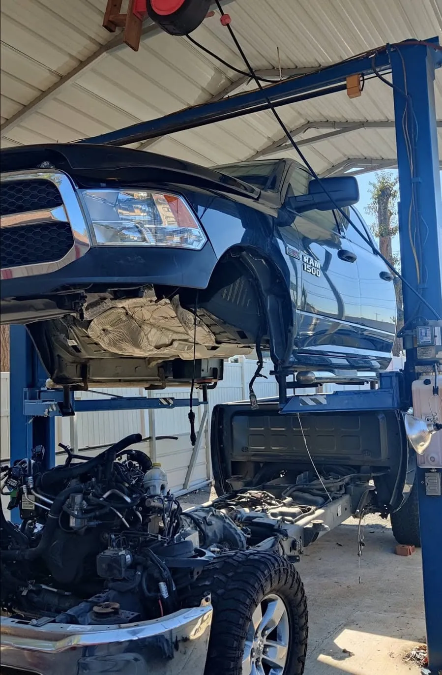 A Ram 1500 raised on a two-post lift at Riverside Automotive with drivetrain components removed for service.
