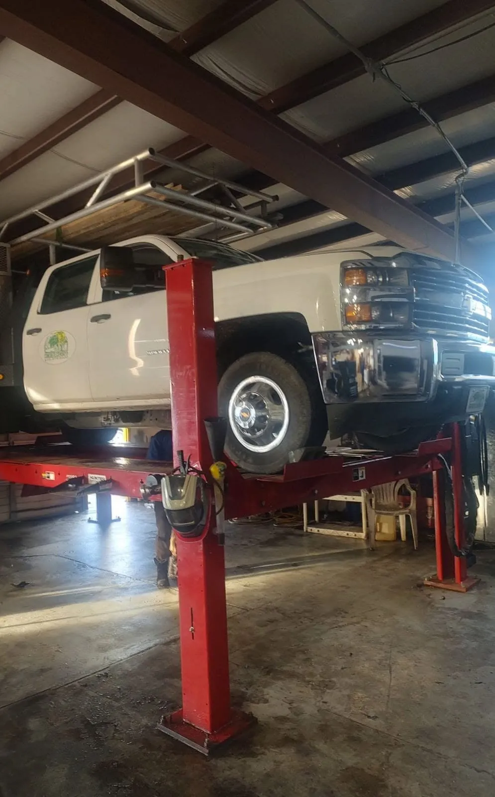 A white Chevrolet work truck up on the four-post rack at Riverside Automotive for fleet service.